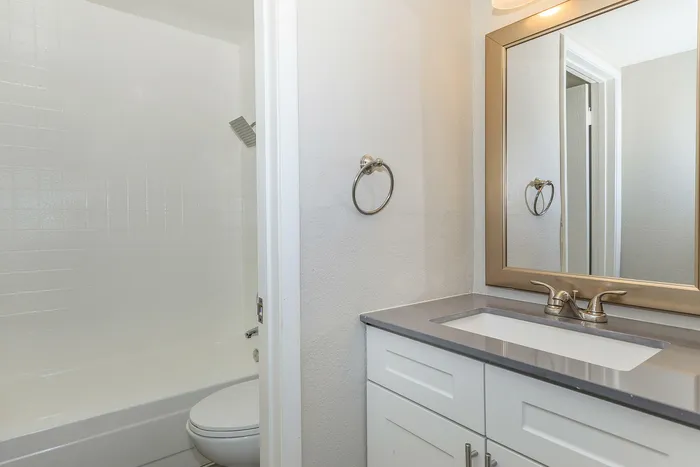 Bright and airy bathroom featuring a modern sink, large mirror, and bathtub with sleek fixtures.