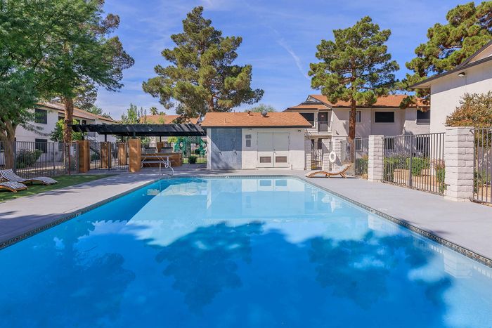 Lush outdoor community pool area with relaxing lounge chairs and vibrant greenery.