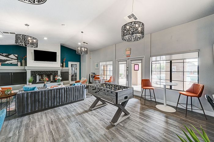 Modern apartment lounge featuring stylish decor, foosball table, elegant seating, and vibrant ambiance.