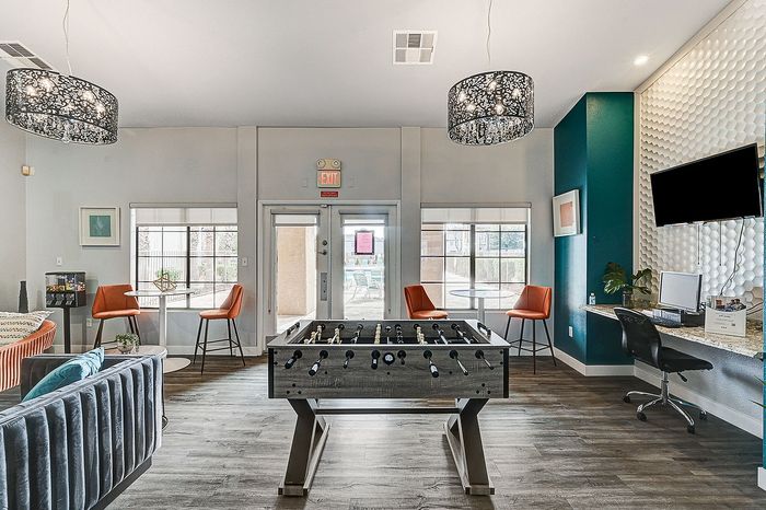 Inviting apartment lounge with modern decor, featuring a foosball table, stylish seating, and a workstation, perfect for relaxation and socializing.