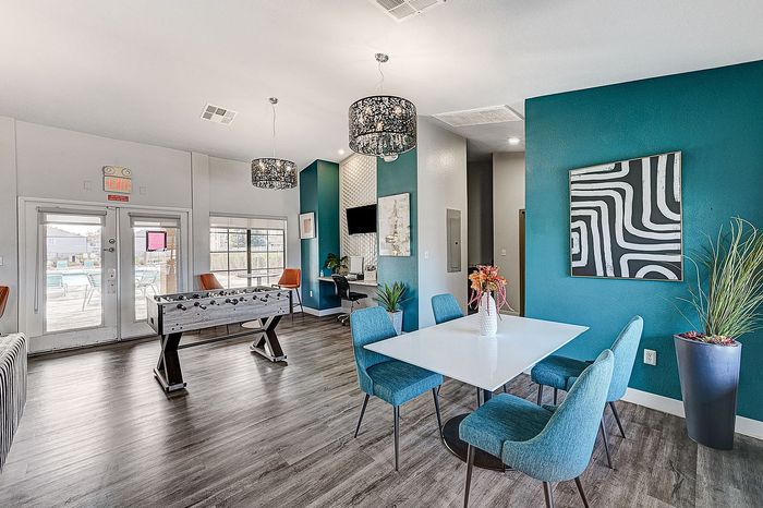 Vibrant communal space with a foosball table, modern decor, and teal accent walls, ideal for socializing and relaxation.