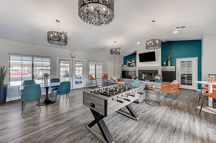 Vibrant communal lounge featuring modern seating, foosball table, and elegant lighting, ideal for socializing and relaxation.