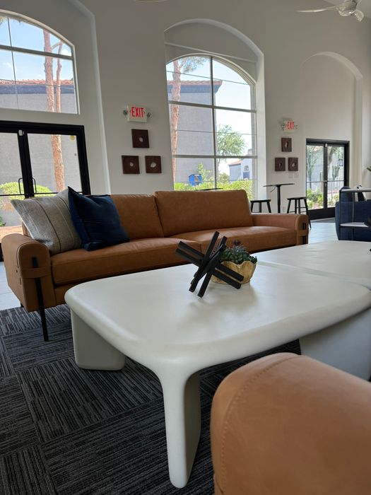 Inviting living space with modern brown leather sofas, large arched windows, and sleek white coffee table in chic apartment setting.