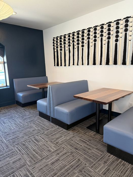 Chic dining area featuring modern blue booths, elegant wall art, and stylish carpet flooring.