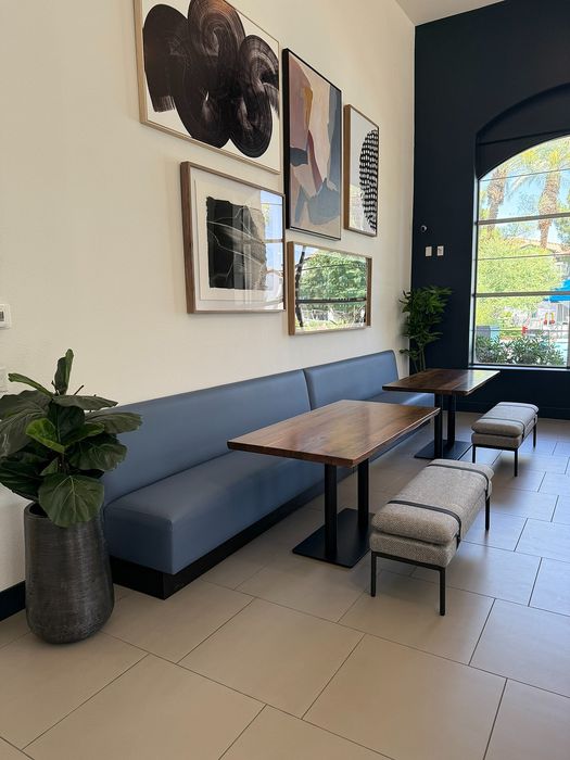 Chic modern seating area with a navy-blue bench, contemporary artwork, and lush greenery, perfect for stylish relaxation.
