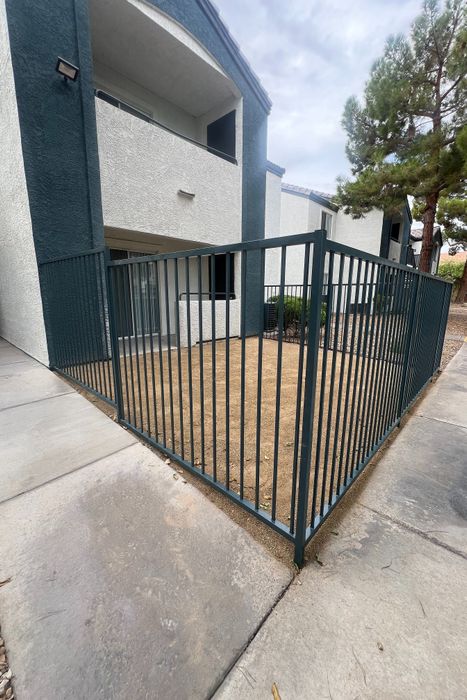 Charming apartment exterior with a private fenced patio, showcasing modern architecture and lush greenery.