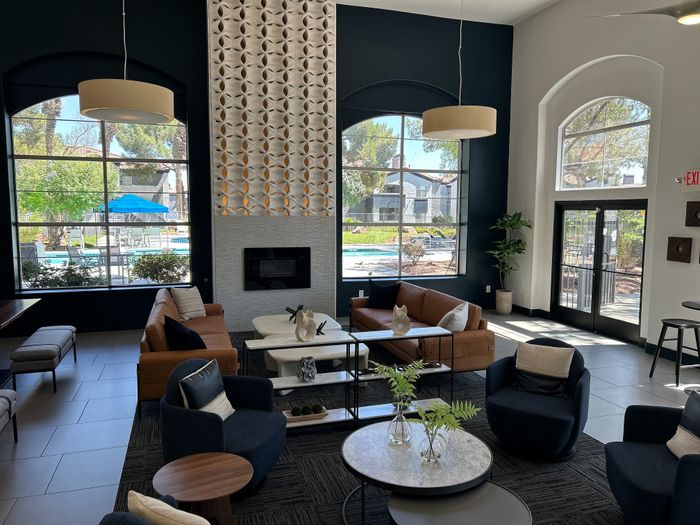 Modern and inviting living space with high ceilings, elegant decor, and large windows overlooking a tranquil garden and pool area.