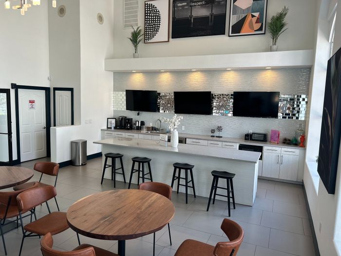 Contemporary open-concept lounge with sleek kitchen island, bar stools, stylish decor, and natural lighting.
