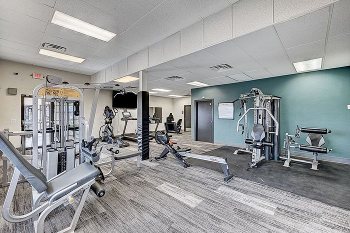 Modern apartment gym with state-of-the-art exercise equipment, sleek flooring, and vibrant wall accents, exuding an energetic and inviting atmosphere.