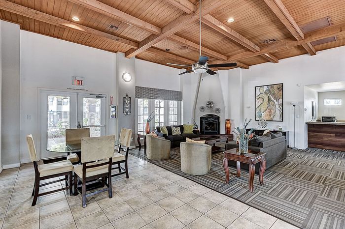 Elegant living area showcasing cozy seating, modern decor, and large windows under a charming wood-beamed ceiling.