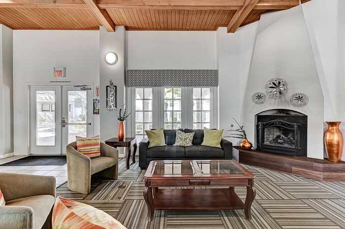 Inviting living area featuring elegant wood-beamed ceiling, cozy fireplace, and modern furnishings with vibrant accents.