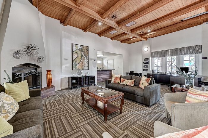 Inviting living room with modern decor, featuring a cozy fireplace, contemporary furniture, and elegant wood beam ceiling.