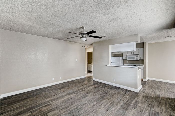 Sleek modern living space with elegant wood floors and open-concept kitchen featuring stylish appliances and ample natural light.