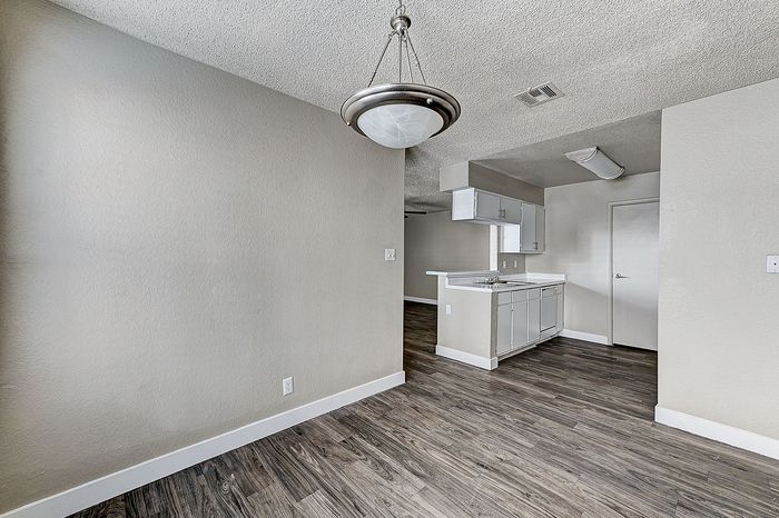 Chic apartment interior showcasing elegant wood flooring, modern lighting, and a sleek kitchen with crisp white cabinetry.