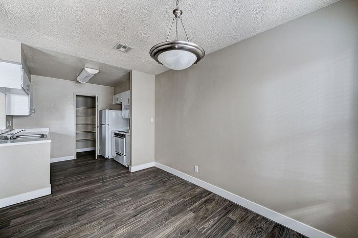 Modern kitchen with elegant wooden flooring, sleek white cabinetry, and ample natural light.