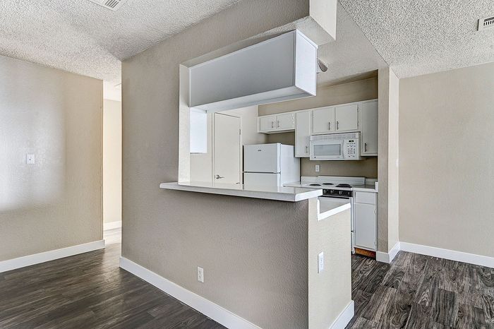 Charming open-concept kitchen with modern white cabinetry and sleek countertops, featuring polished wood flooring for a cozy, inviting atmosphere.