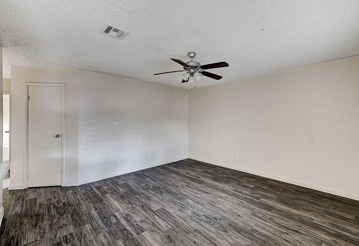 Inviting empty room with elegant wood flooring, neutral walls, and a modern ceiling fan, ideal for custom interior design.