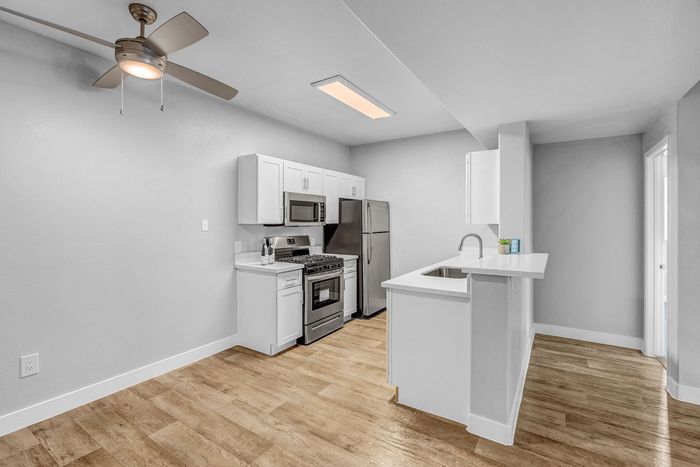 Modern kitchen with sleek stainless steel appliances, elegant white cabinetry, and warm wood flooring, creating a perfect blend of style and function.