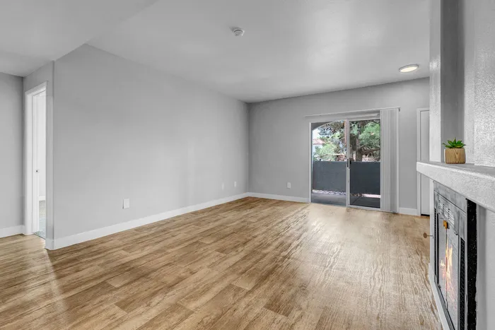 Inviting apartment living room with elegant wood flooring, fireplace, and garden-view sliding doors offering natural light.