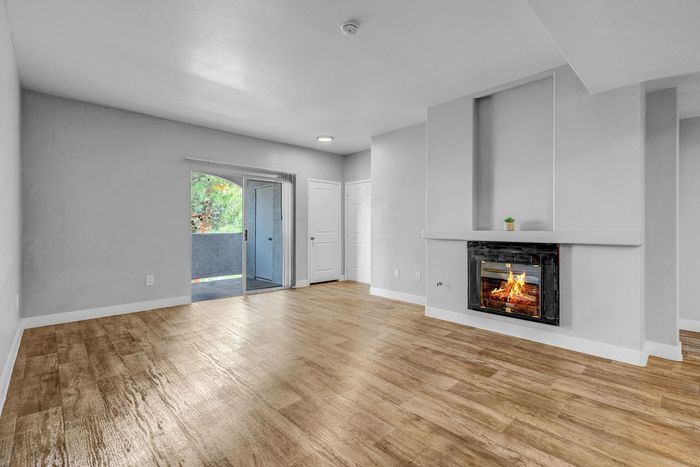 Bright and spacious living room with elegant hardwood floors, cozy fireplace, and sliding glass doors leading to a scenic balcony.