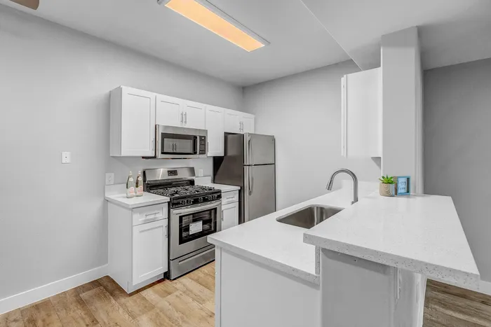 Contemporary kitchen with sleek white cabinets, modern stainless steel appliances, and elegant countertops.