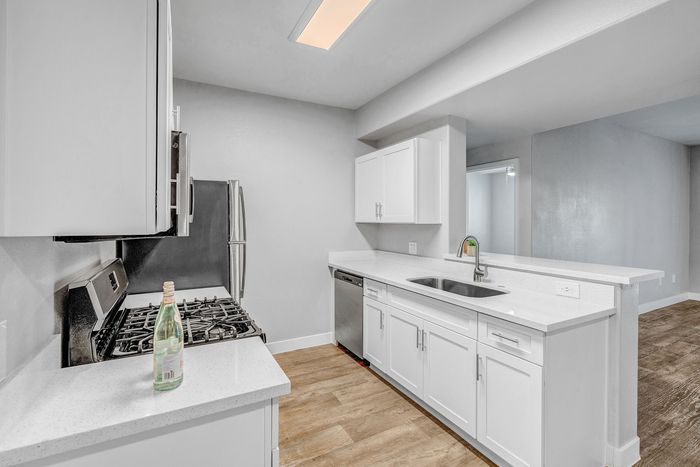 Modern kitchen with sleek white cabinetry, spacious countertops, and stainless steel appliances, perfect for culinary creativity.