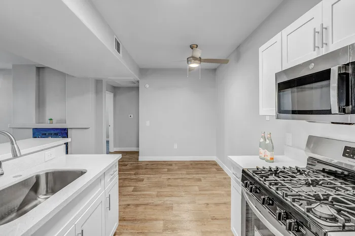 Inviting modern kitchen with sleek stainless steel appliances, stylish white cabinetry, and elegant wood flooring.