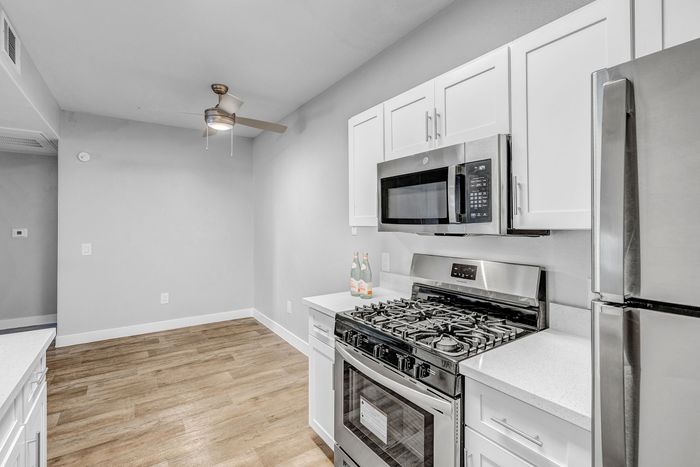 Modern kitchen with sleek stainless steel appliances, spacious cabinets, and elegant wood flooring. Ideal for culinary enthusiasts.