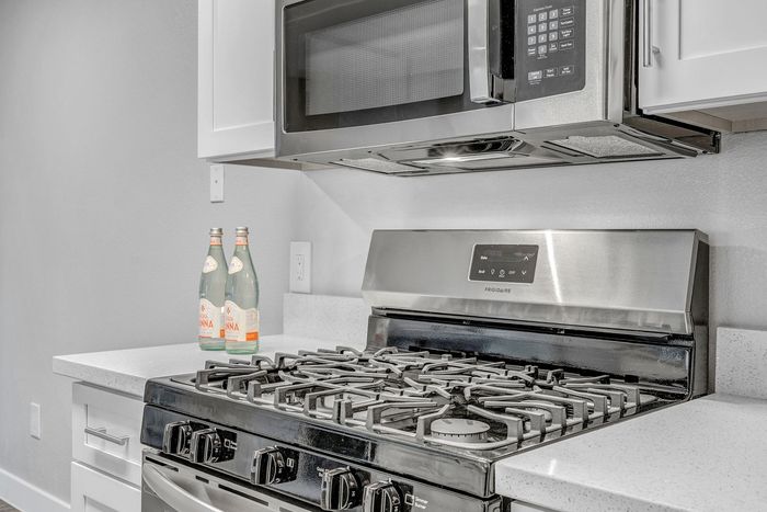 Modern kitchen featuring a sleek stainless steel stove and microwave, complemented by elegant white cabinetry and sparkling countertops.