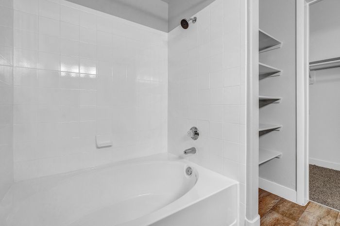 Modern bathroom featuring a sleek white bathtub, tiled walls, and convenient built-in shelves for storage.