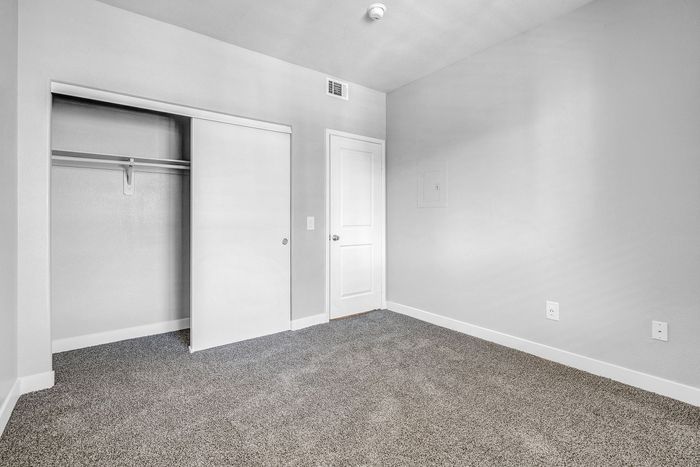 Bright and inviting bedroom featuring plush carpeting, a spacious closet, and modern finishes.