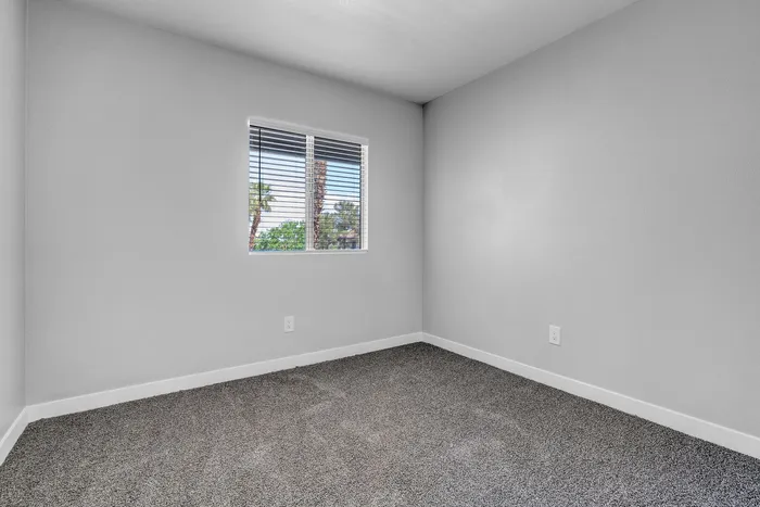 Bright, modern room featuring fresh carpeting and a window with scenic views, perfect for a cozy bedroom or stylish office.