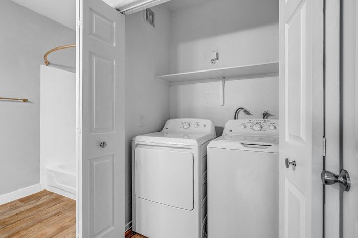 Modern laundry area with sleek washer and dryer, ample storage, and elegant wood flooring.