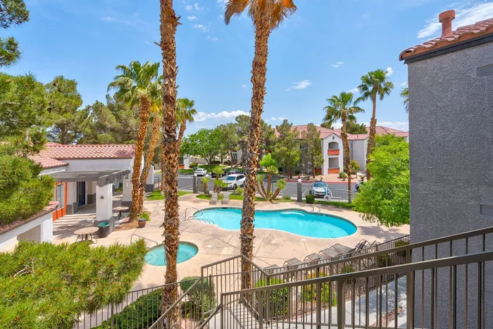 Charming apartment complex with a refreshing pool and spa, surrounded by lush palm trees and vibrant greenery, offering a perfect oasis for relaxation.