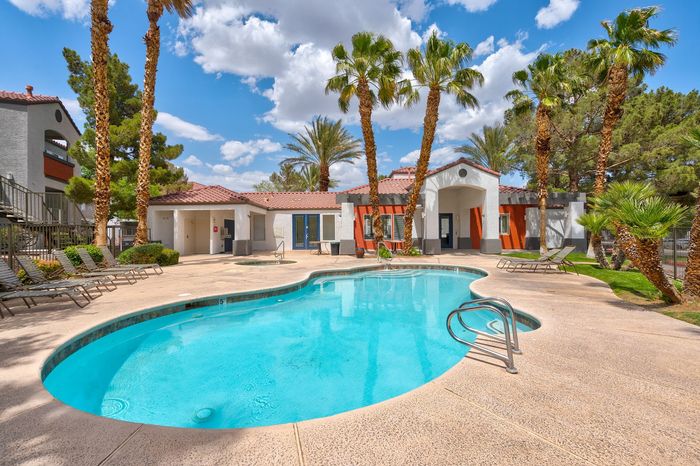 Luxurious outdoor pool area with palm trees and modern clubhouse, perfect for relaxation and social gatherings.