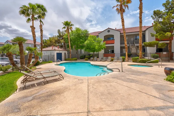 Serene apartment community with refreshing pool area, surrounded by lush palm trees and contemporary buildings.
