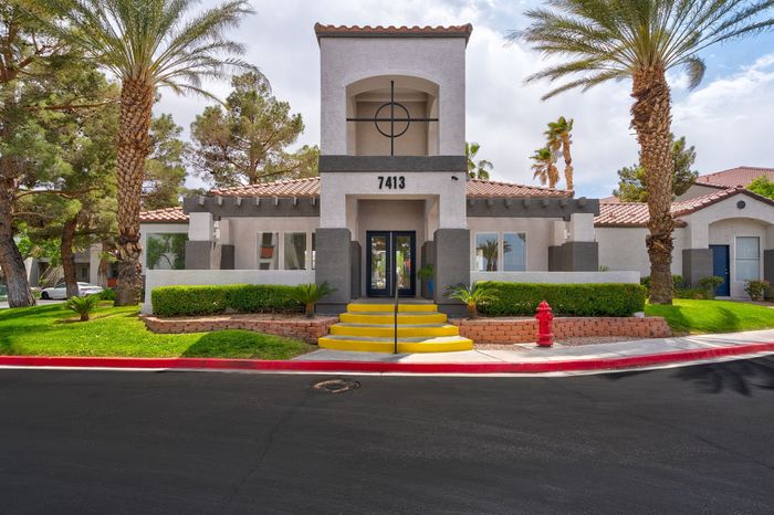 Charming apartment complex exterior showcasing elegant architecture with lush palm trees and vibrant landscaping, inviting entrance with bold yellow steps and modern design accents.