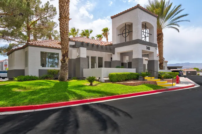 Charming modern apartment complex with inviting entrance, surrounded by lush greenery and palm trees, offering a serene living environment.