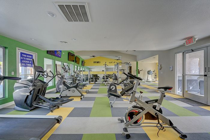 Vibrant modern gym with state-of-the-art equipment, colorful flooring, and ample natural light.