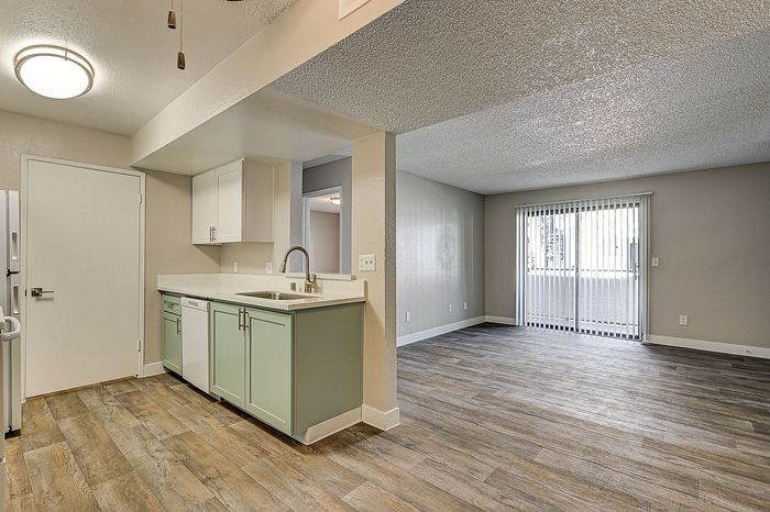 Contemporary open-plan apartment with sleek hardwood floors, featuring a modern kitchen and spacious living area with large windows.