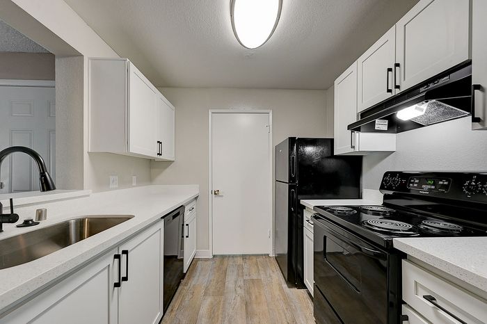 Modern kitchen with sleek black appliances, elegant white cabinetry, and spacious countertops, offering a stylish and functional cooking space.