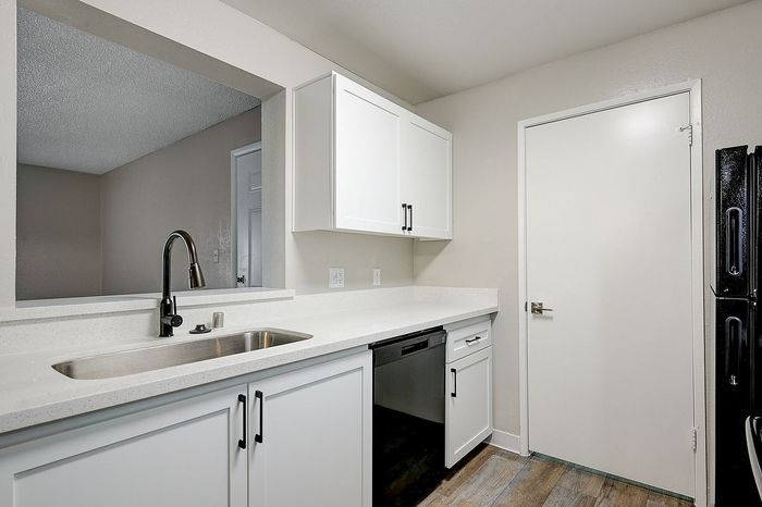 Modern kitchen with sleek white cabinetry, stainless steel sink, and contemporary black fixtures.