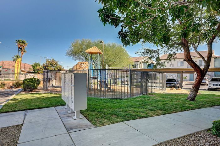 Charming outdoor space featuring a secure playground, lush greenery, and convenient mailboxes, perfect for family-friendly living.