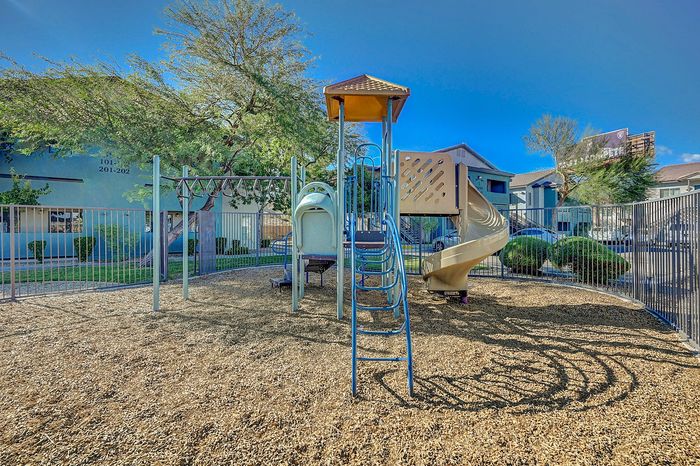 Inviting playground with a slide and climbing structures surrounded by vibrant greenery, perfect for family fun and outdoor play.