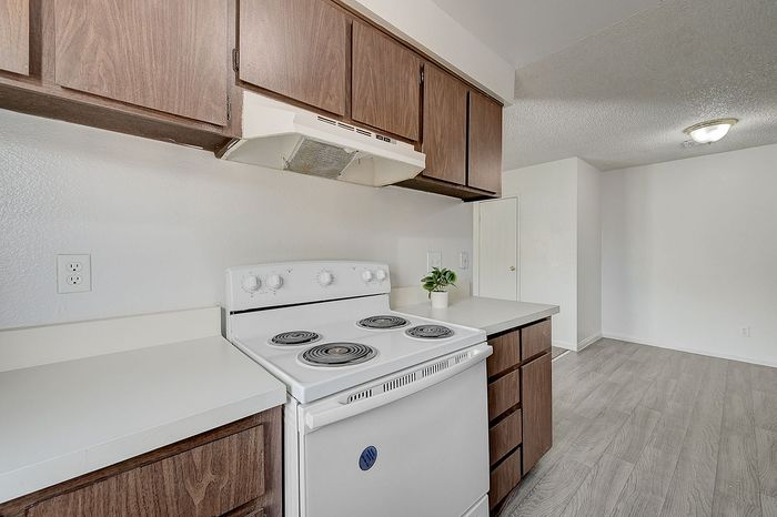 Chic kitchen with sleek white countertops, modern appliances, and elegant wood cabinetry. Bright and inviting space for cooking enthusiasts.