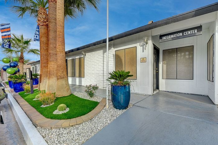 Charming apartment information center exterior with vibrant planters and palm trees, creating an inviting atmosphere.