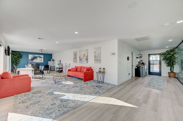 Bright and inviting open-concept office space featuring vibrant red sofas, stylish decor, and modern furnishings with large windows letting in natural light.