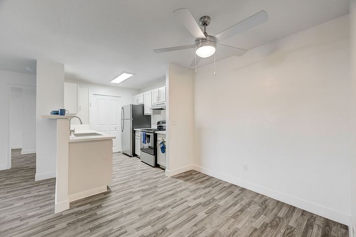 Modern open-plan kitchen with sleek appliances, wood-style flooring, and a ceiling fan for efficient ventilation.