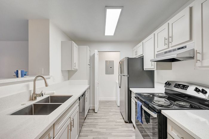Modern kitchen with sleek white cabinets, stainless steel appliances, and elegant countertops in a bright, spacious setting.