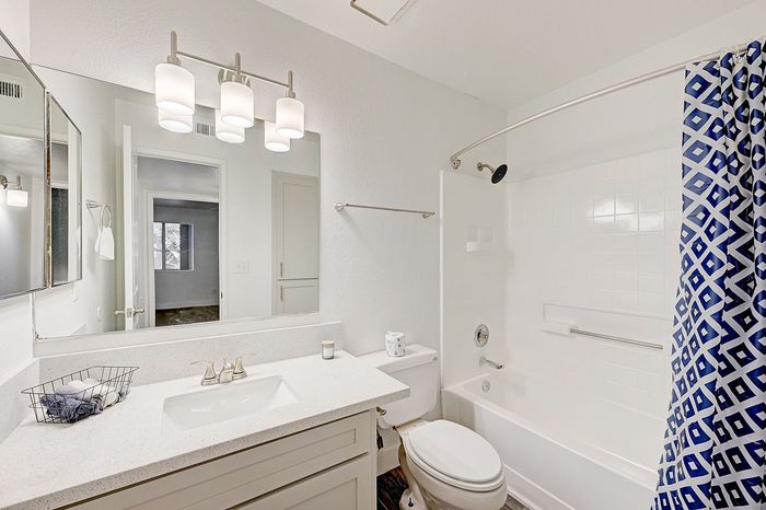Modern bathroom with elegant lighting, sleek vanity, and stylish blue geometric shower curtain, offering a refreshing and inviting space.